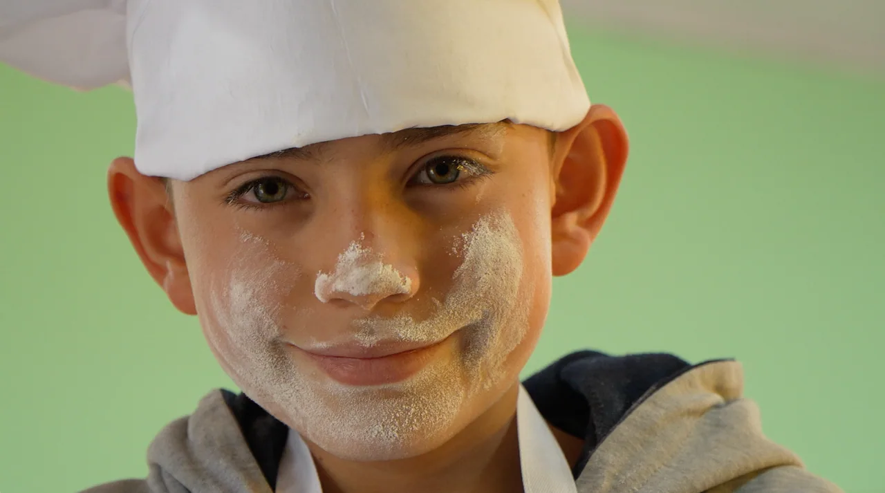 Child wearing a chef's hat with flour on his face
